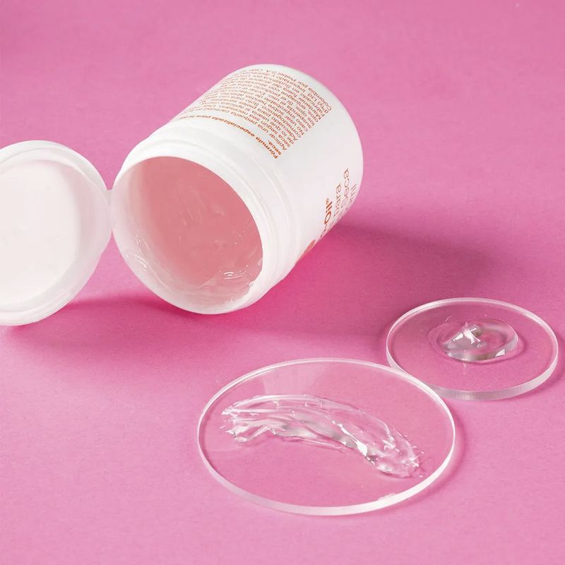 Bio-Oil-Gel-para-Piel-Seca-50ml-con-muestras-de-su-textura-transparente-sobre-fondo-rosa.-Crema-hidratante-para-piel-seca