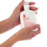 Dos-manos-sosteniendo-una-botella-blanca-de-Bio-Oil-Body-Lotion-de-250ml.-Se-visualiza-la-etiqueta-con-el-logo-de-Bio-Oil-el-nombre-del-producto-en-ingles-el-tamaño-y-parte-de-las-instrucciones-de-uso.
