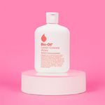 botella-de-Bio-Oil-Locion-Corporal-de-250ml-sobre-un-pedestal-blanco.-Fondo-rosa-y-etiqueta-del-producto-visible.