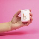 Bio-Oil-Gel-para-Piel-Seca-100ml.-Frasco-blanco-sostenido-por-una-mano-sobre-fondo-rosa.-Crema-hidratante-para-la-piel-seca