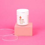 Bote-de-100ml-del-gel-para-piel-seca-Bio-Oil-colocado-sobre-un-bloque-rosa.-Alrededor-dos-discos-transparentes.-El-fondo-es-de-color-rosa-uniforme.