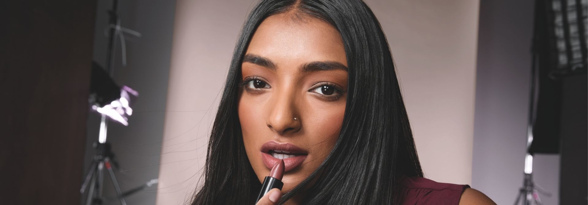 Mujer morena aplicándose un labial rojo en barra